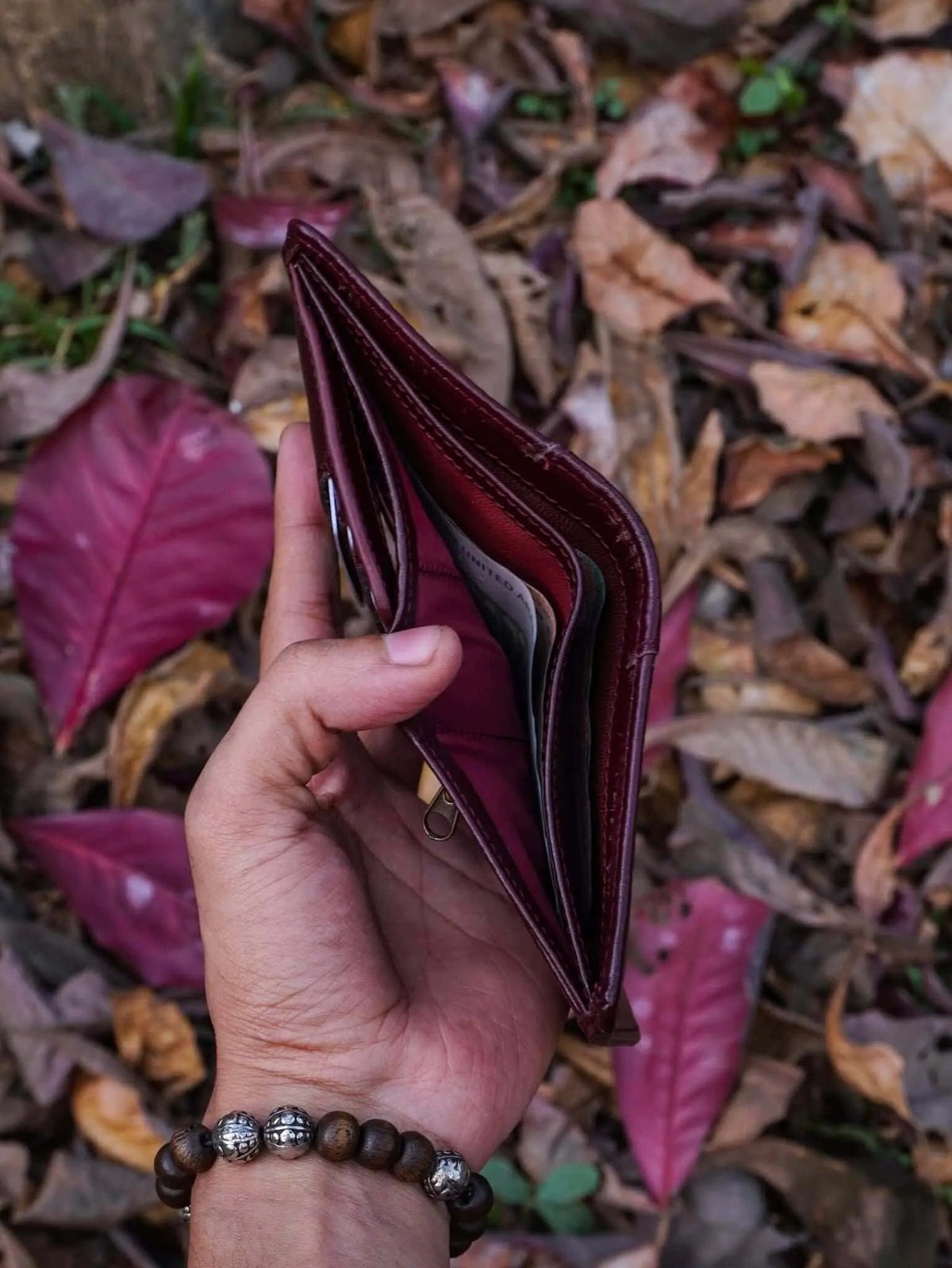 Interior view of an open burgundy leather trifold wallet featuring custom slots for sim and memory cards