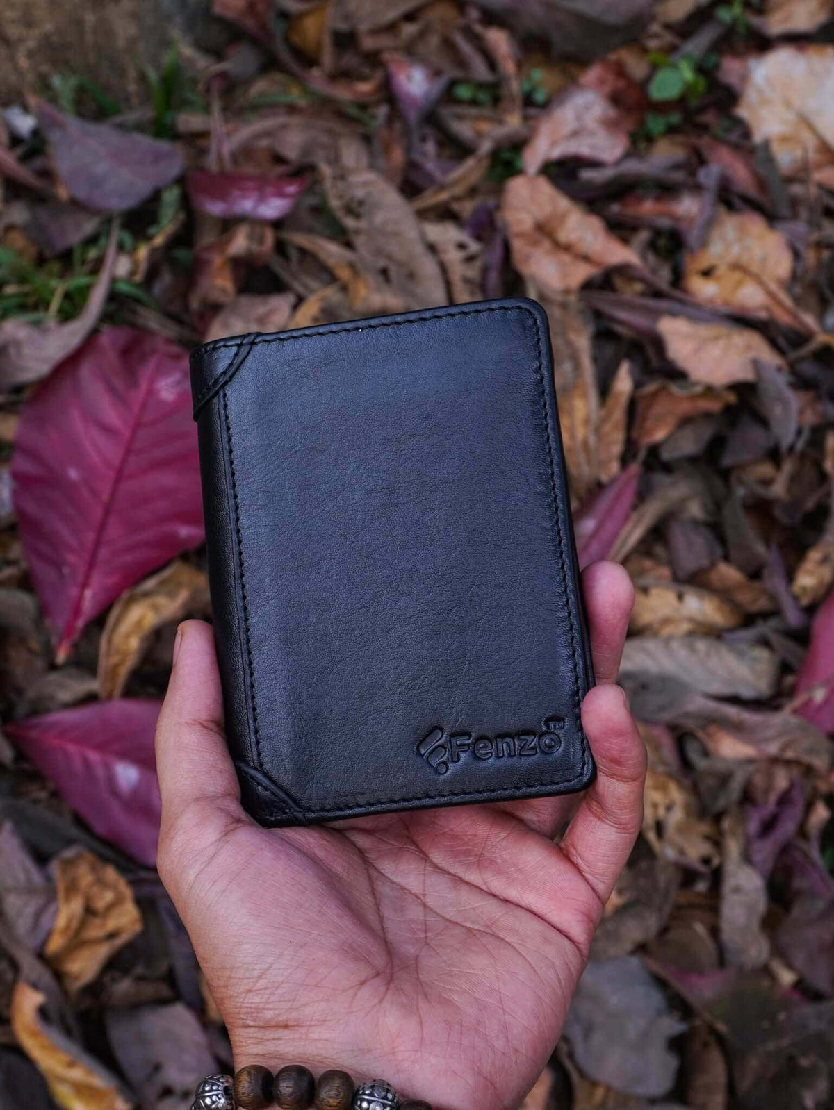 Handheld shot of Fenzo classic black genuine leather vertical trifold wallet with embossed brand logo